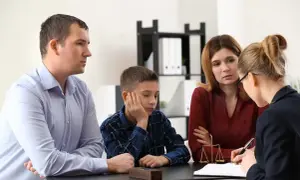 Rodzina z synem rozmawia z prawniczką, która wyjaśnia, co to kurator. Na stole waga sprawiedliwości.