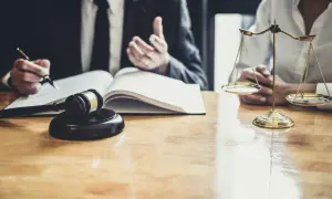 Prawnik przy biurku z młotkiem sędziowskim i wagą sprawiedliwości, omawiający, ile kosztuje notariusz przy darowiznie.