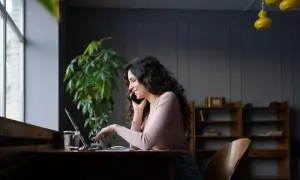 Kobieta rozmawia przez telefon, pracując przy laptopie, szukając informacji jak zmienić kody PKD w CEIDG.