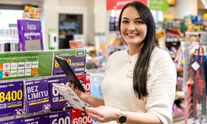 Uśmiechnięta pracownica w sklepie z ofertami telefonii komórkowej. W tle półki z kartami SIM i starterami. Czy to jest właśnie ten model franczyzy, o którym słyszałeś?