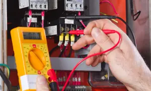 Elektromonter z multimetrem sprawdza instalację elektryczną. To praca wymagająca precyzji, zgodna z zawodem elektromonter kod 311101.
