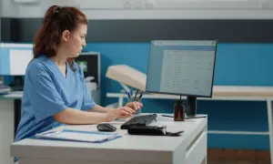 Rejestratorka medyczna kod zawodu pracuje przy komputerze, wprowadzając dane pacjentów.