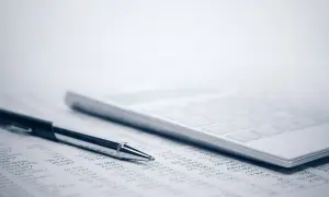Długopis i kalkulator na arkuszu z danymi. To narzędzia pracy, które pomagają w analizie finansowej, niezbędne dla każdego, kto ma kod zawodu kierownik.