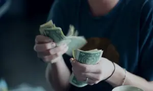 Dłonie liczą banknoty dolarowe. Kto to jest płatnik? Osoba, która przekazuje pieniądze.