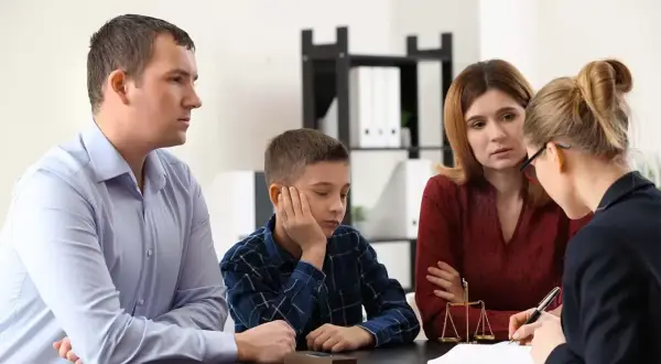 Rodzina z synem rozmawia z prawniczką, która wyjaśnia, co to kurator. Na stole waga sprawiedliwości.