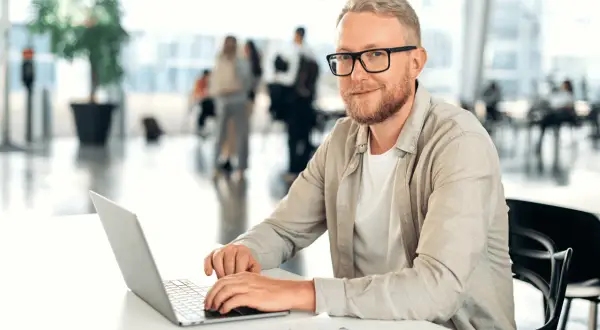 Mężczyzna w okularach, z brodą, pracuje na laptopie. Jego kod zawodu to informatyk, który tworzy cyfrowe rozwiązania.