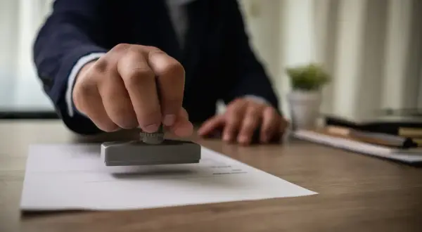 Dłoń z pieczęcią notarialną nad dokumentem. Zastanawiasz się, ile kosztuje porada notarialna?