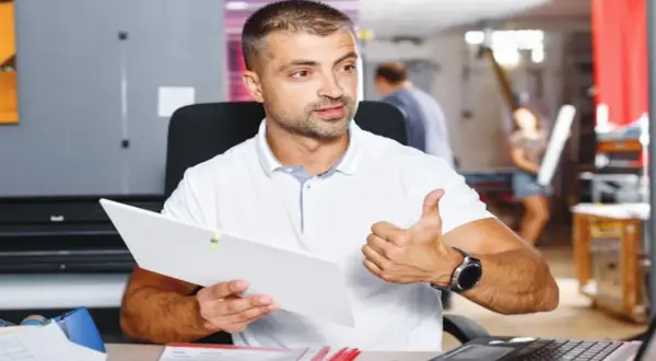 Mężczyzna z dokumentem i kciukiem w górze, pokazujący jak znaleźć kod PKD.