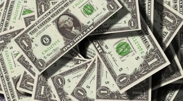 Stosy dolarowych banknotów. Kto ponosi koszty działu spadku u notariusza? Pieniądze mogą pomóc w tej kwestii.
