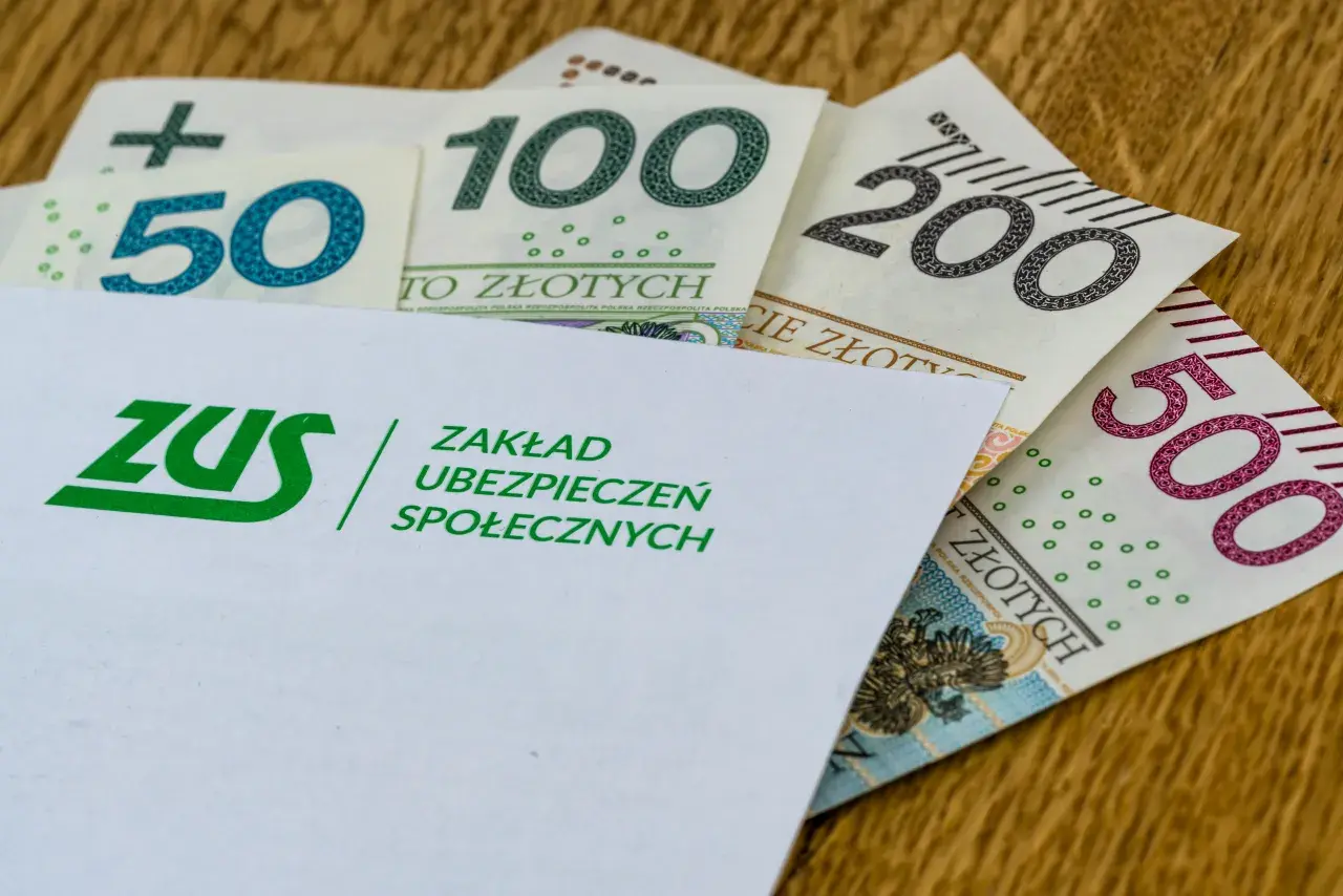 Koperta ZUS z logo i napisami "Zakład Ubezpieczeń Społecznych" na tle polskich banknotów 50, 100, 200 i 500 zł. To symbol tego, co to jest renta.