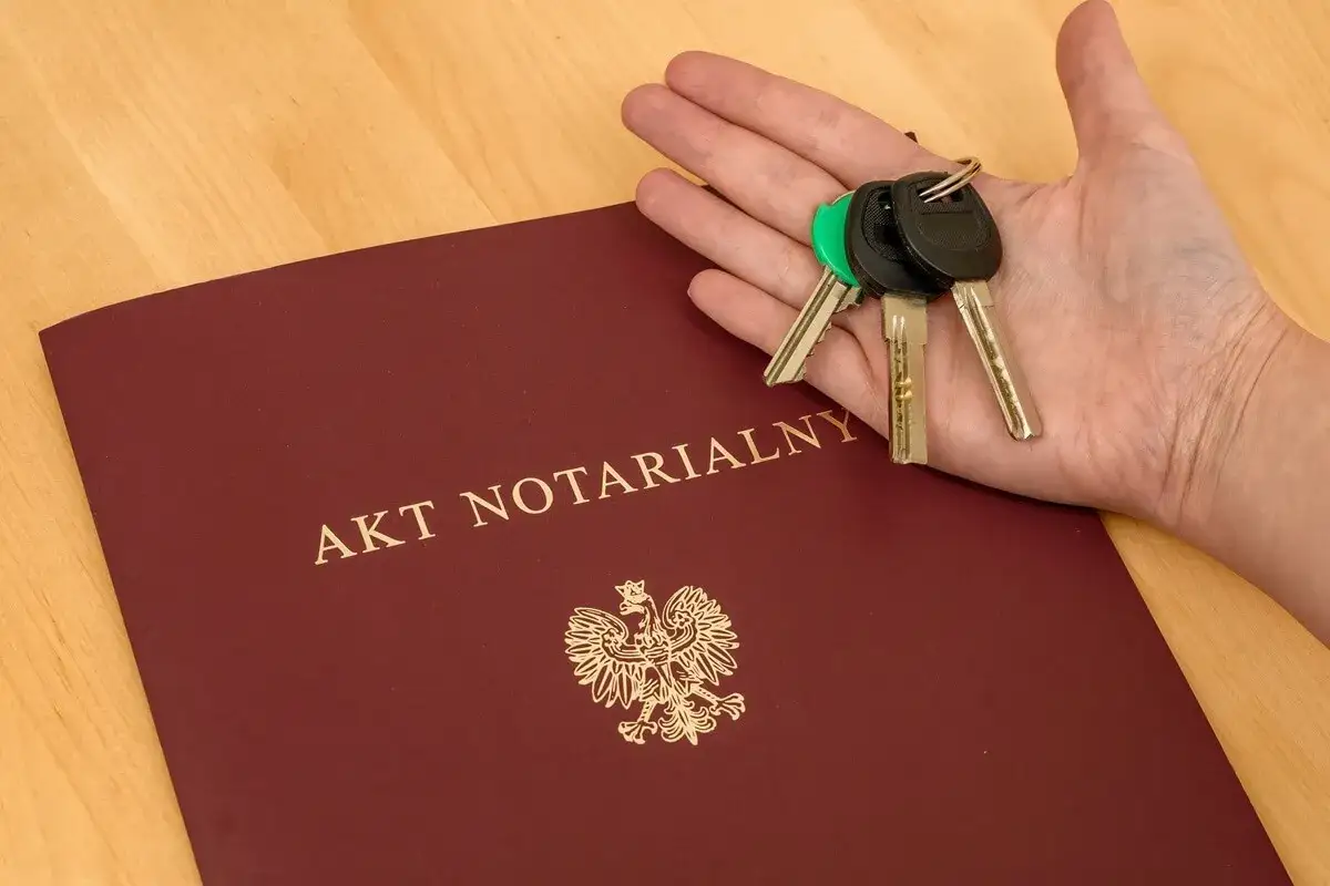 Akt notarialny i klucze symbolizują umowę dożywocia na czym polega: przekazanie nieruchomości w zamian za opiekę.