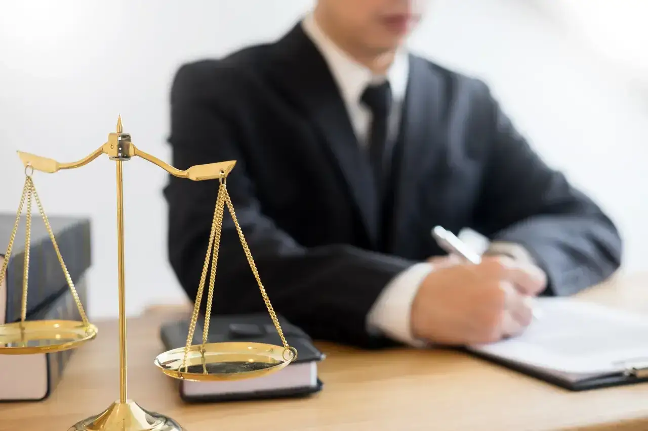 Radca prokuratorii generalnej pochyla się nad dokumentami, obok wagi sprawiedliwości.