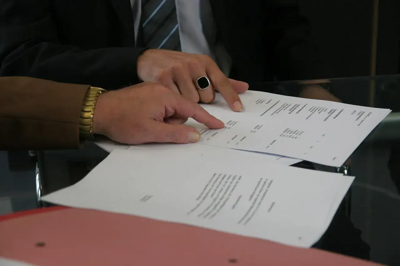 Dwaj mężczyźni omawiają dokumenty, być może ustalając, ile kosztuje akt poświadczenia dziedziczenia.