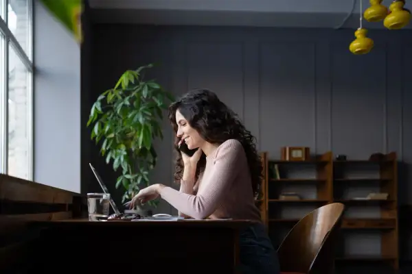Kobieta rozmawia przez telefon, pracując przy laptopie, szukając informacji jak zmienić kody PKD w CEIDG.
